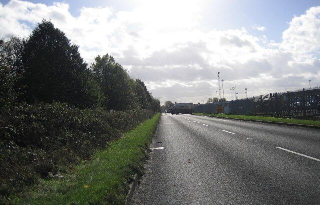 Road near Oil Depot. This long, straight stretch of road is alongside a small part of Kingsbury Oil Depot. It is fortunate that it is long and straight, so that the fully laden tankers can pull out easily. This road also acts like a mini bypass for the village of Kingsbury.