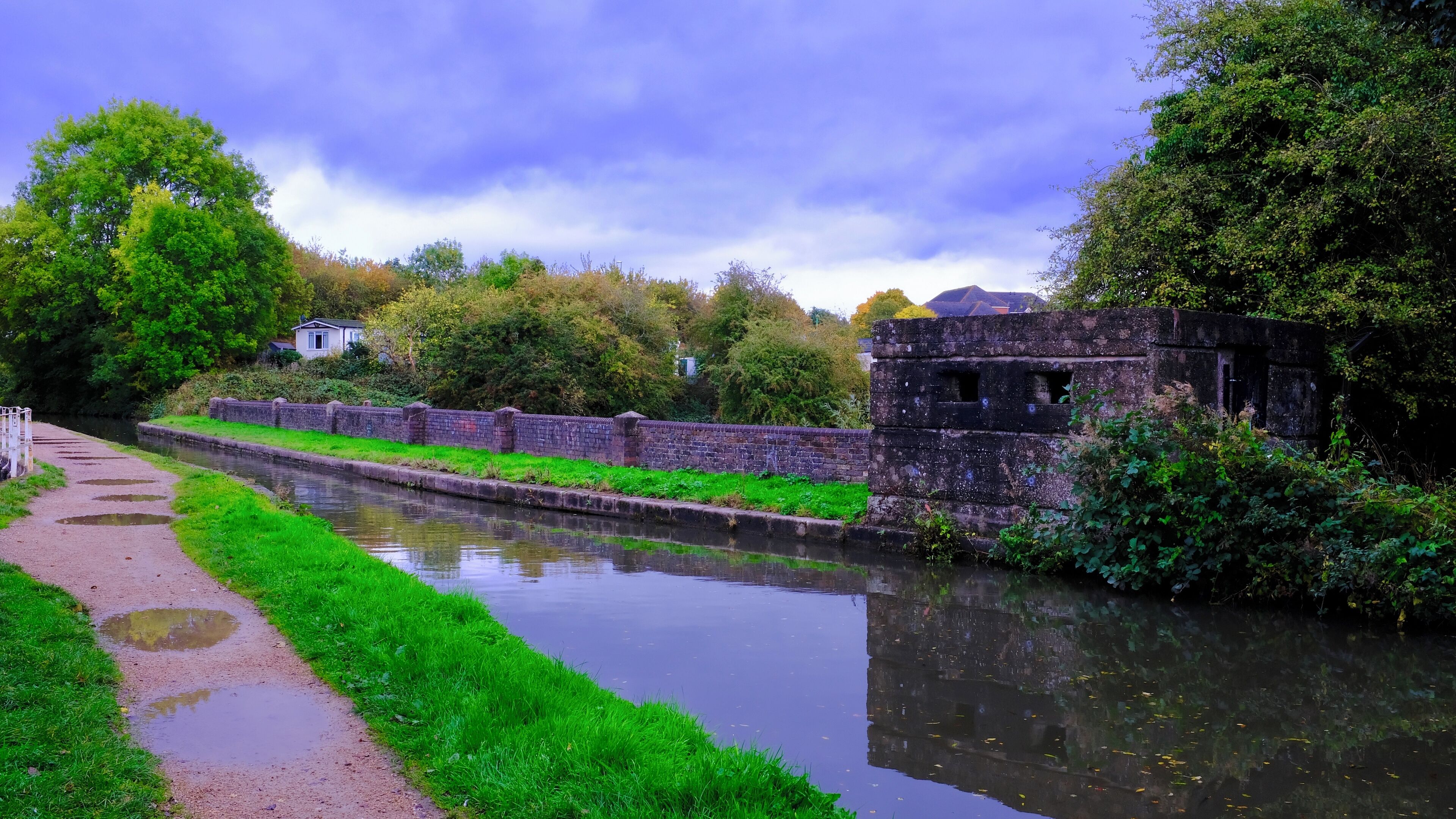 A canal with a brick wall and a pathway alongside.