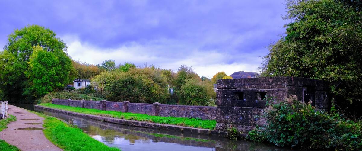 A canal with a brick wall and a pathway alongside.