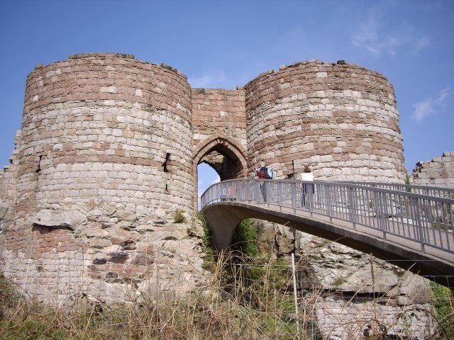 A stone castle with two large towers and a bridge leading to an arched entrance.
