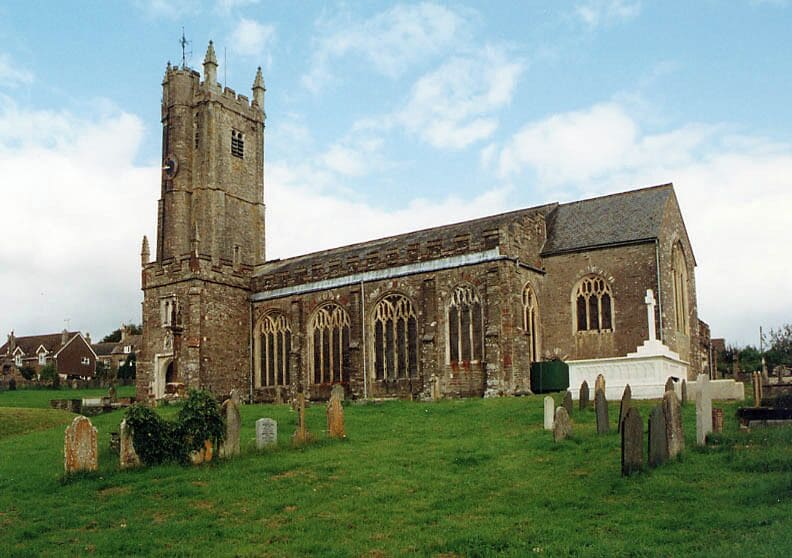 A historic church with a tall tower and a graveyard in front.