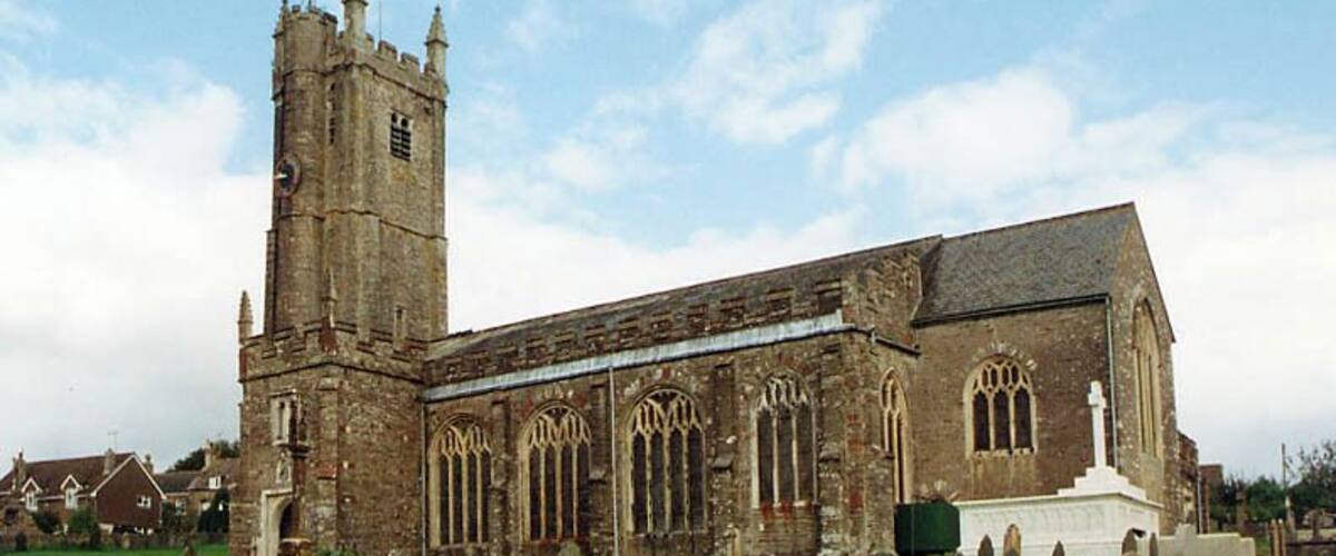 A historic church with a tall tower and a graveyard in front.