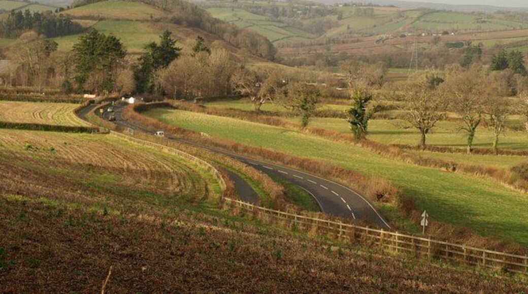 A384 below Huxham's Cross. The main road to the west of 1080828, as it sweeps round bends while descending to cross the River Dart. The prominent hill on the left is 156150.