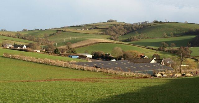 Rolling green hills, a small village with houses, and a large solar farm.