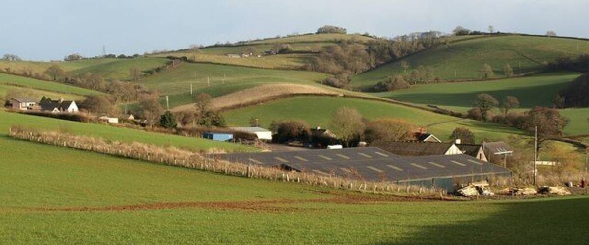 Rolling green hills, a small village with houses, and a large solar farm.