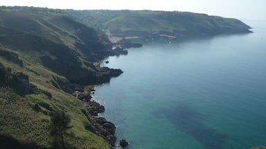Paisagem costeira com colinas verdes e mar tranquilo.