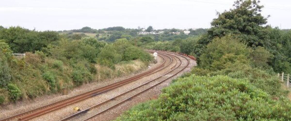 Railway tracks curving through a hilly landscape with dense greenery.