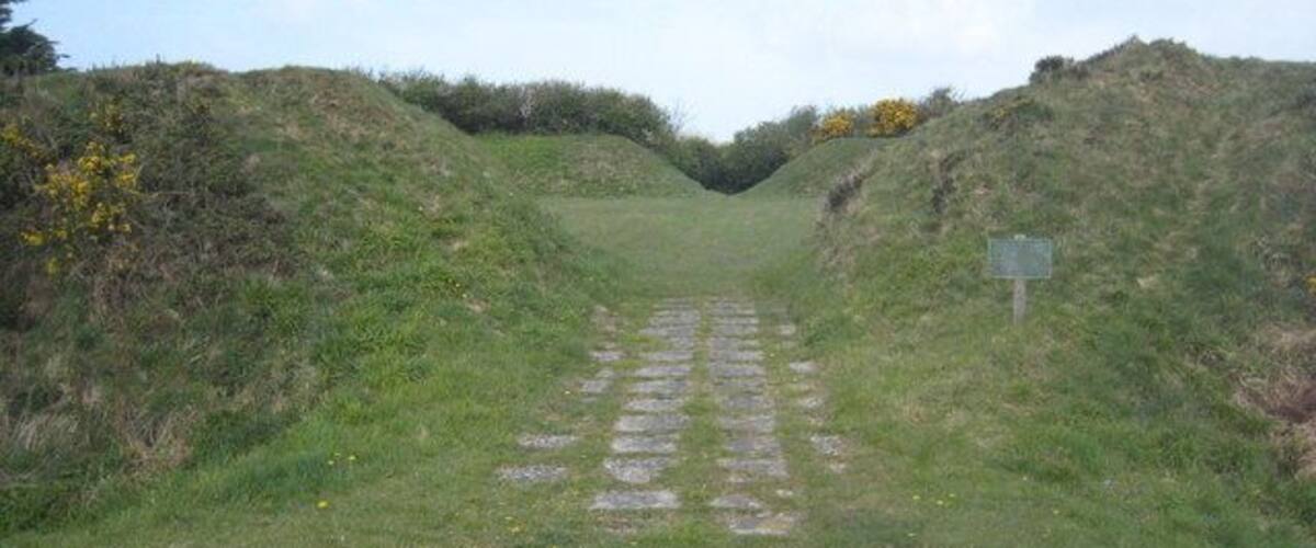 A grassy path leading uphill with a signpost on the right.