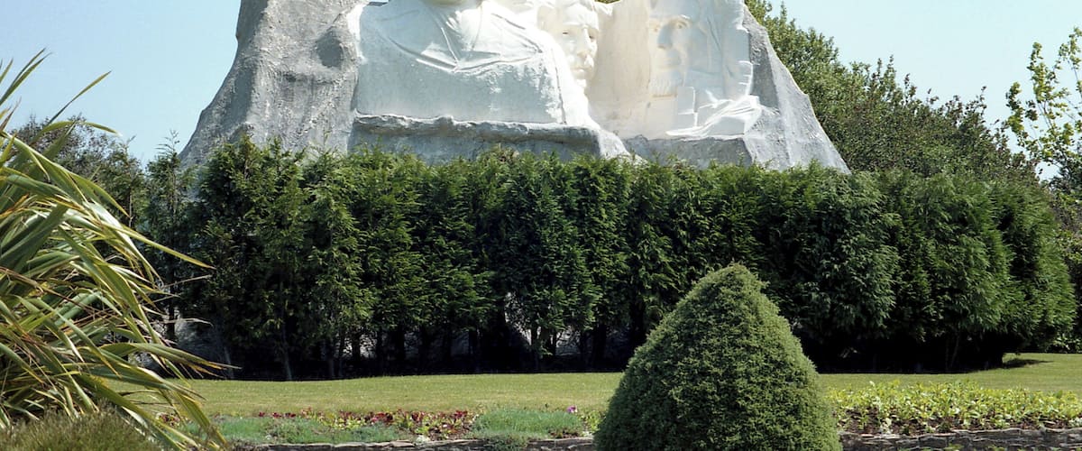 A large white statue of a man and woman in a garden setting.