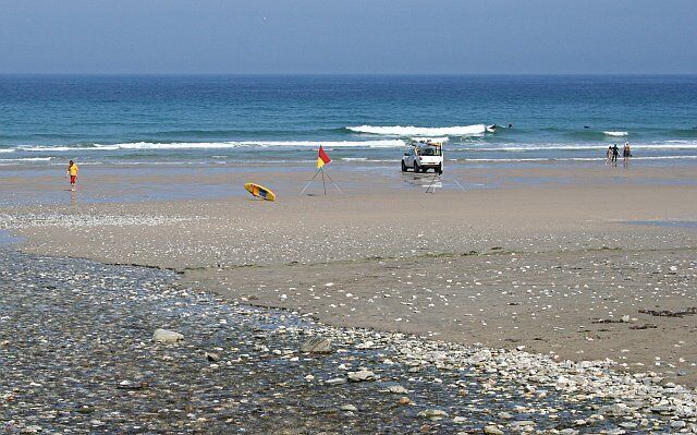 Porthtowan Beach. Not many people on the beach on this hot Summer day. It is June however. The scene here in late July or August would be much more crowded. The landrover belongs to the beach lifeguards who are keeping a close eye on the surfers at this state of the tide (half out).