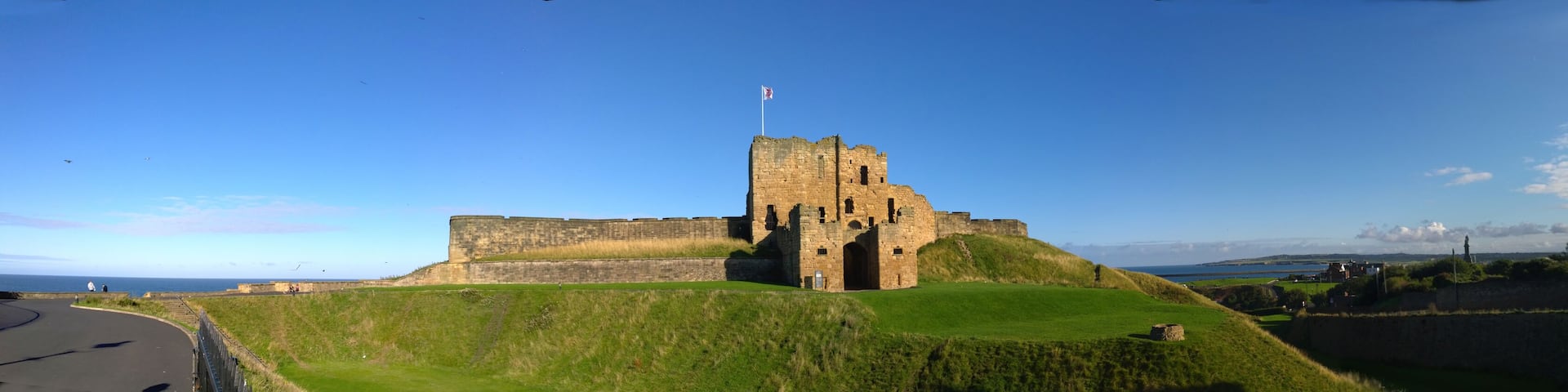 A historic castle on a grassy hill with a clear sky.