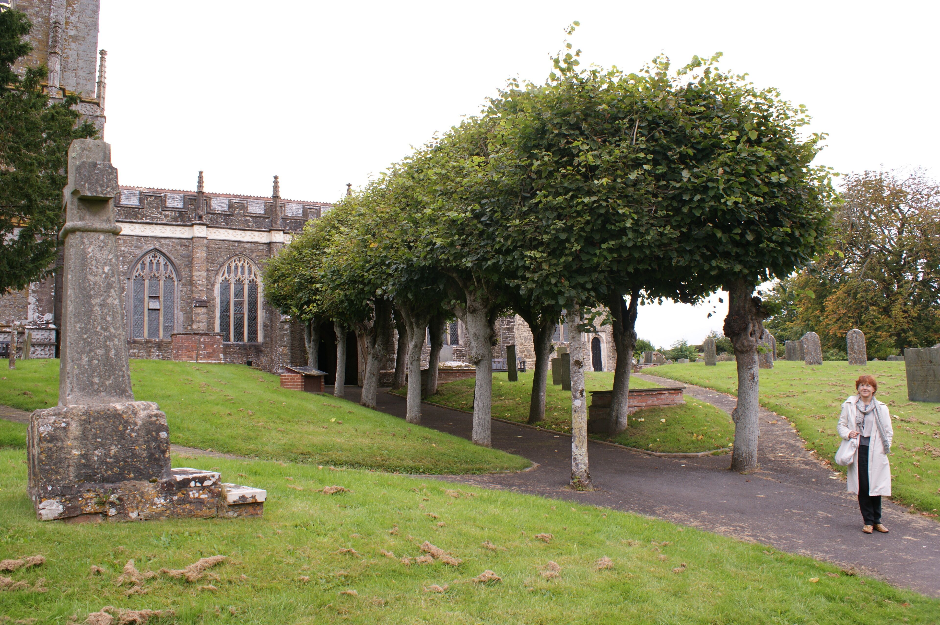 A cemetery with gravestones, a church, and a woman walking.