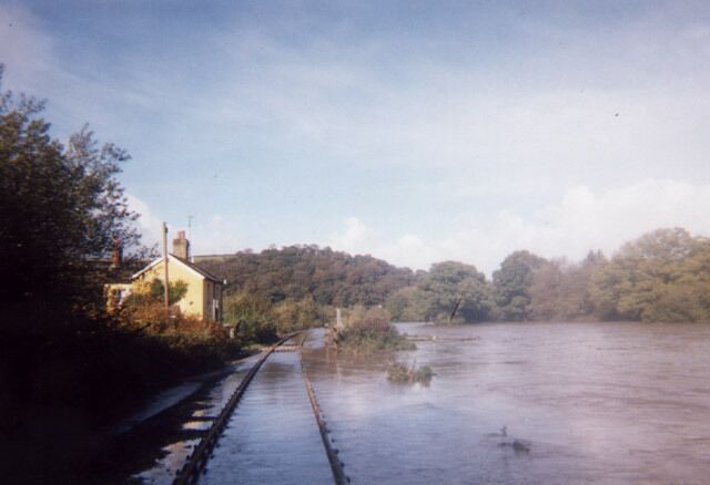 Higher Doomsford Crossing / River Taw. This photo is taken on the Exeter to Barnstaple railway branch line, looking North. The railway, completed in 1854, runs next to the River Taw for this stretch. This was taken in the flood of October 2000. The railway acts as a levee protecting the crossing keeper's cottage.