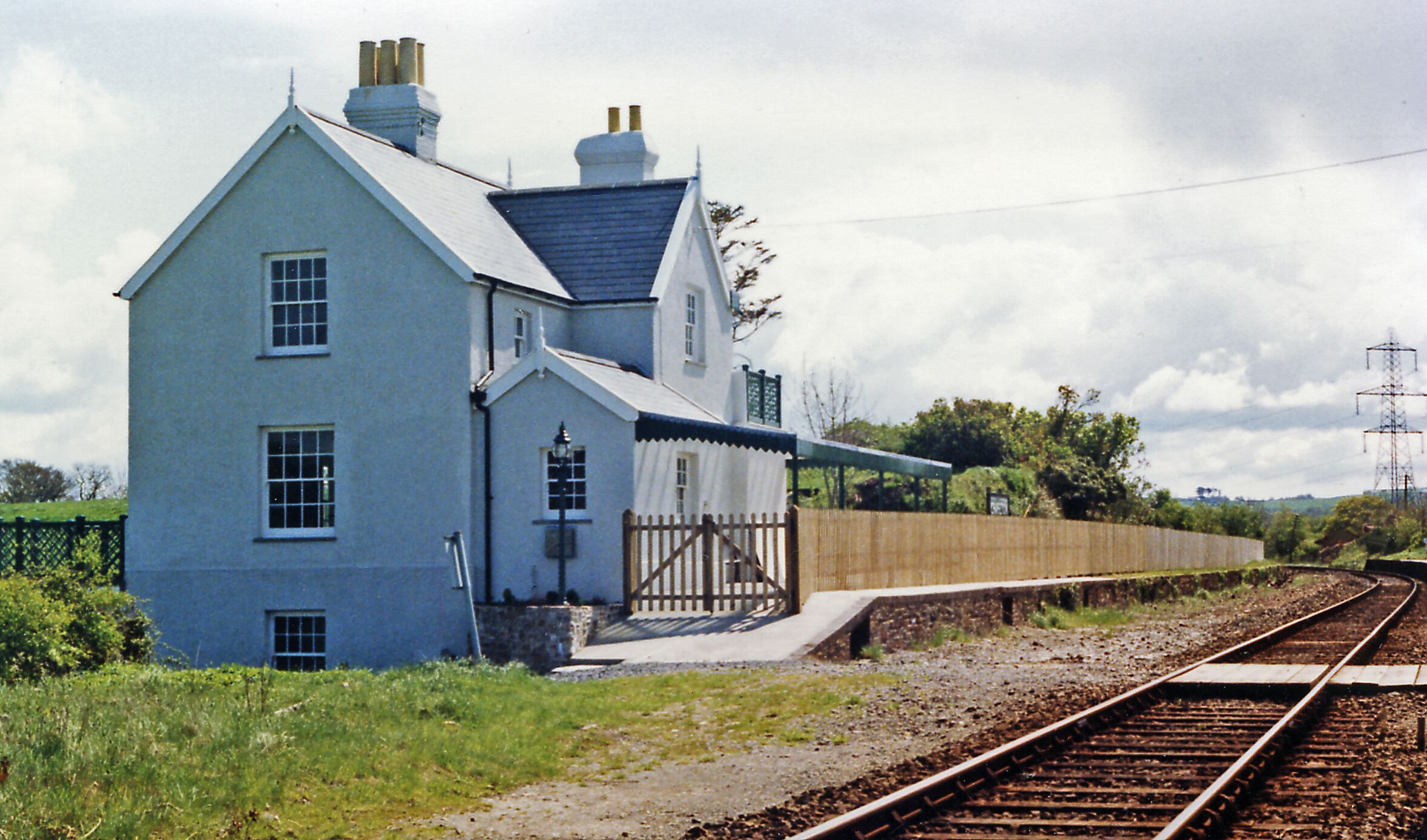 A blue house with a white roof near railway tracks.
