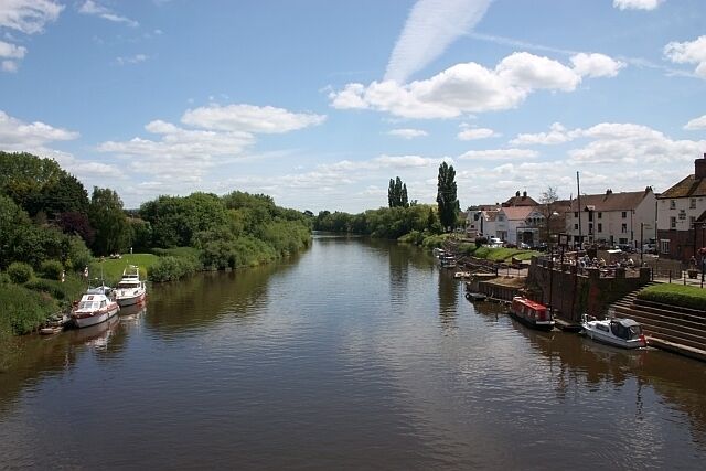 A river with boats, greenery, and buildings along the banks.