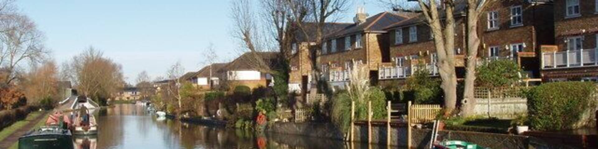 Canal with houses on Jacks Lane View from towpath bridge over the spillway from the canal to the River Colne. The houses have a frontage onto Jacks Lane, and gardens with moorings on the canal.