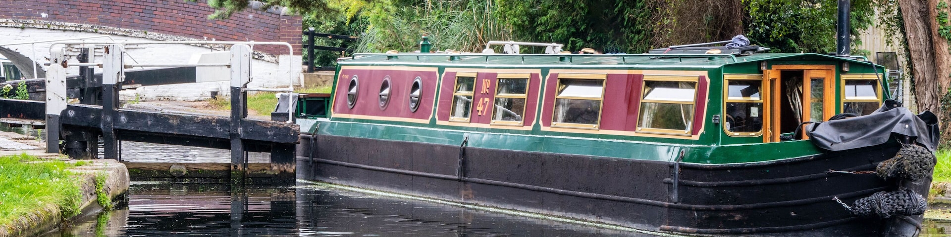 A narrowboat on a canal with a bridge in the background.