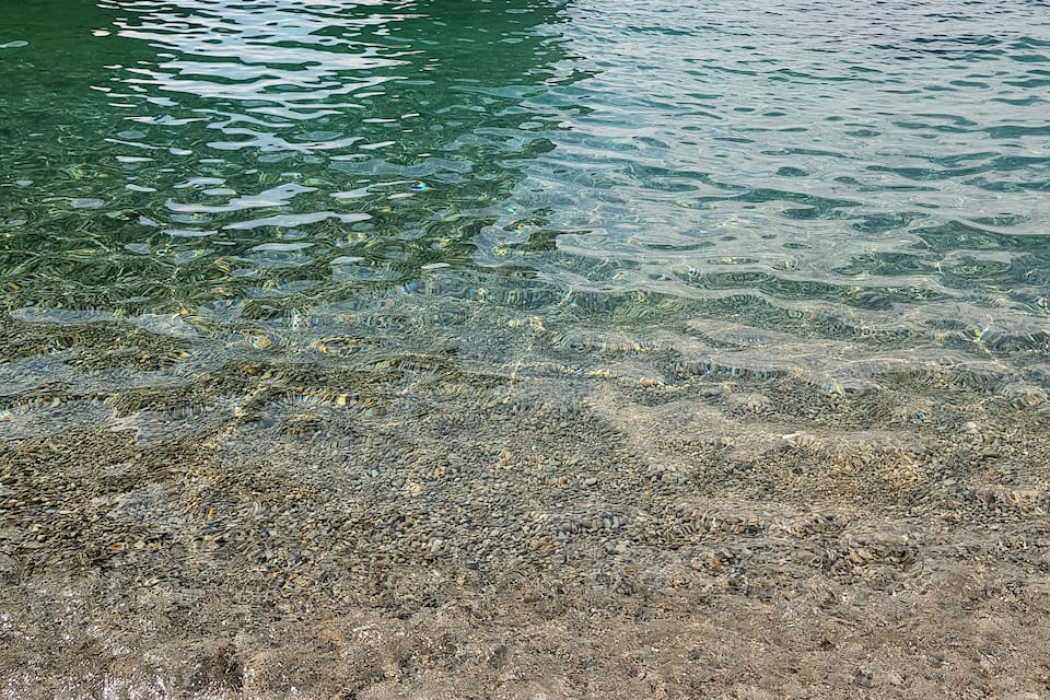 A clear blue sea with a rocky arch formation.