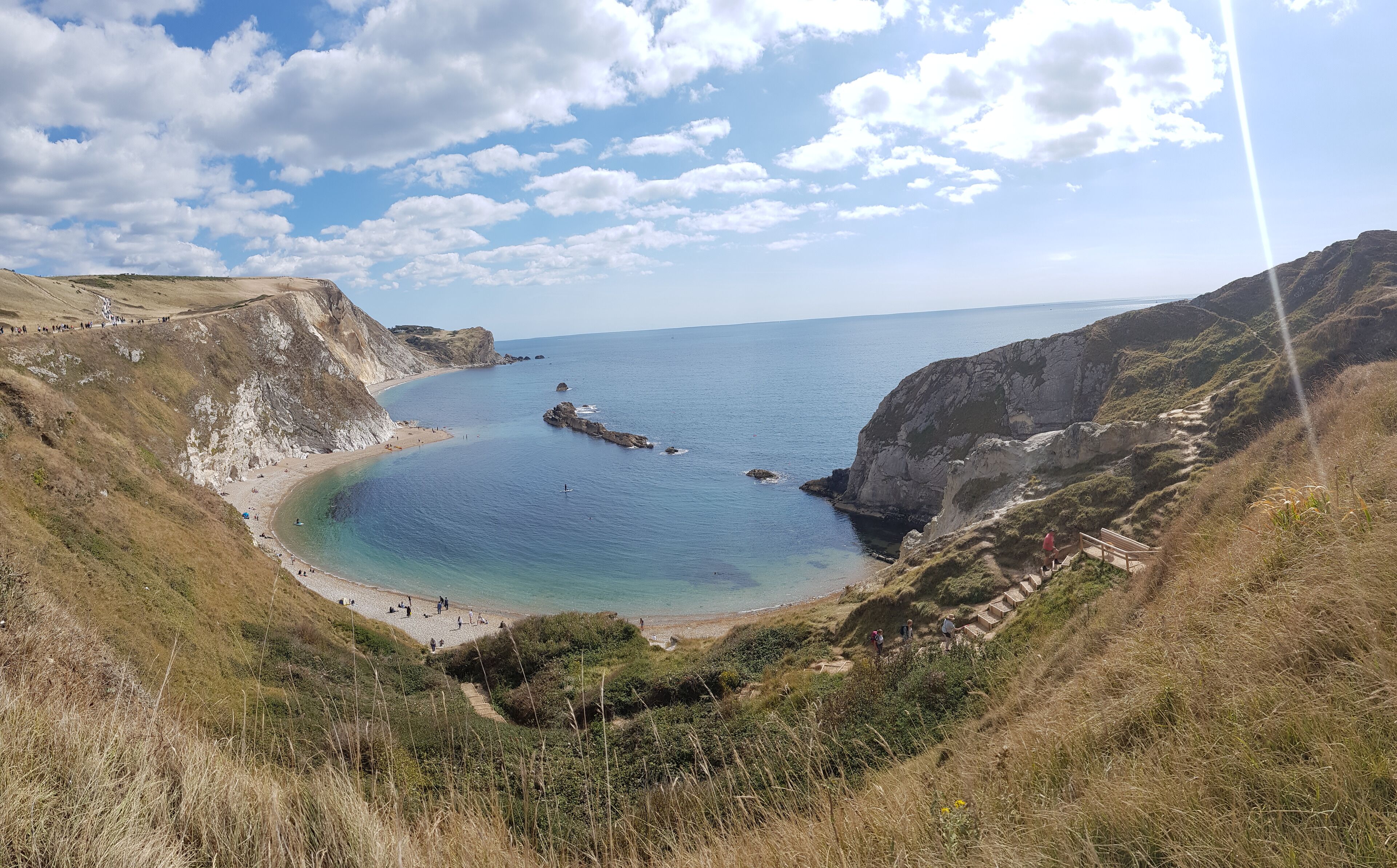 A coastal landscape with a beach, cliffs, and a clear sky.