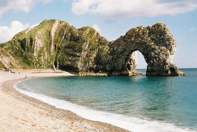 A beach with a natural rock arch formation.