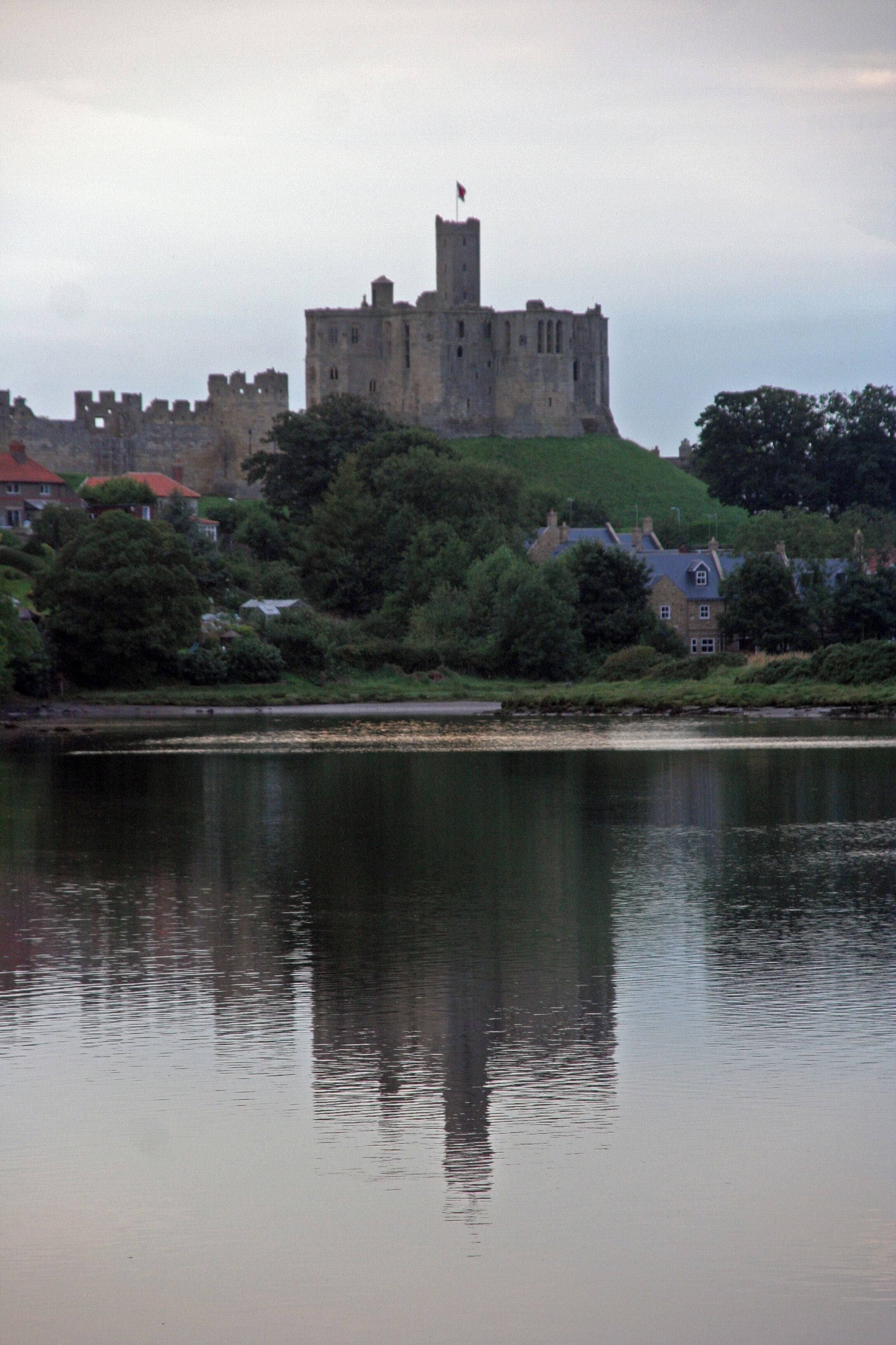 A castle on a hill with a body of water in the foreground.