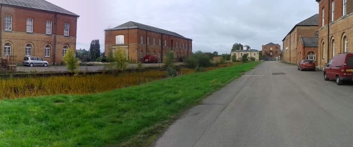 A canal with brick buildings on either side, a blue door, and parked cars.