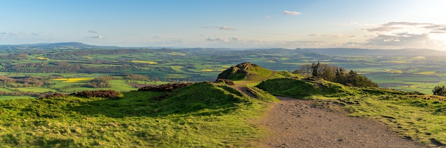 A grassy hill with a rocky outcrop and a winding path.
