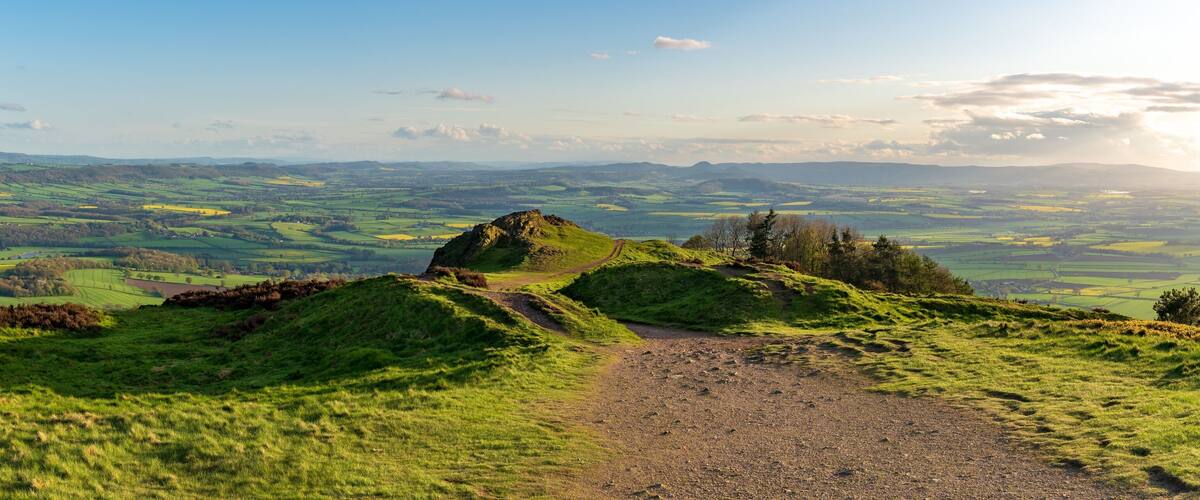 A grassy hill with a rocky outcrop and a winding path.