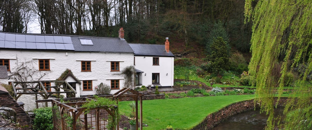 A white house with a garden and a stream.