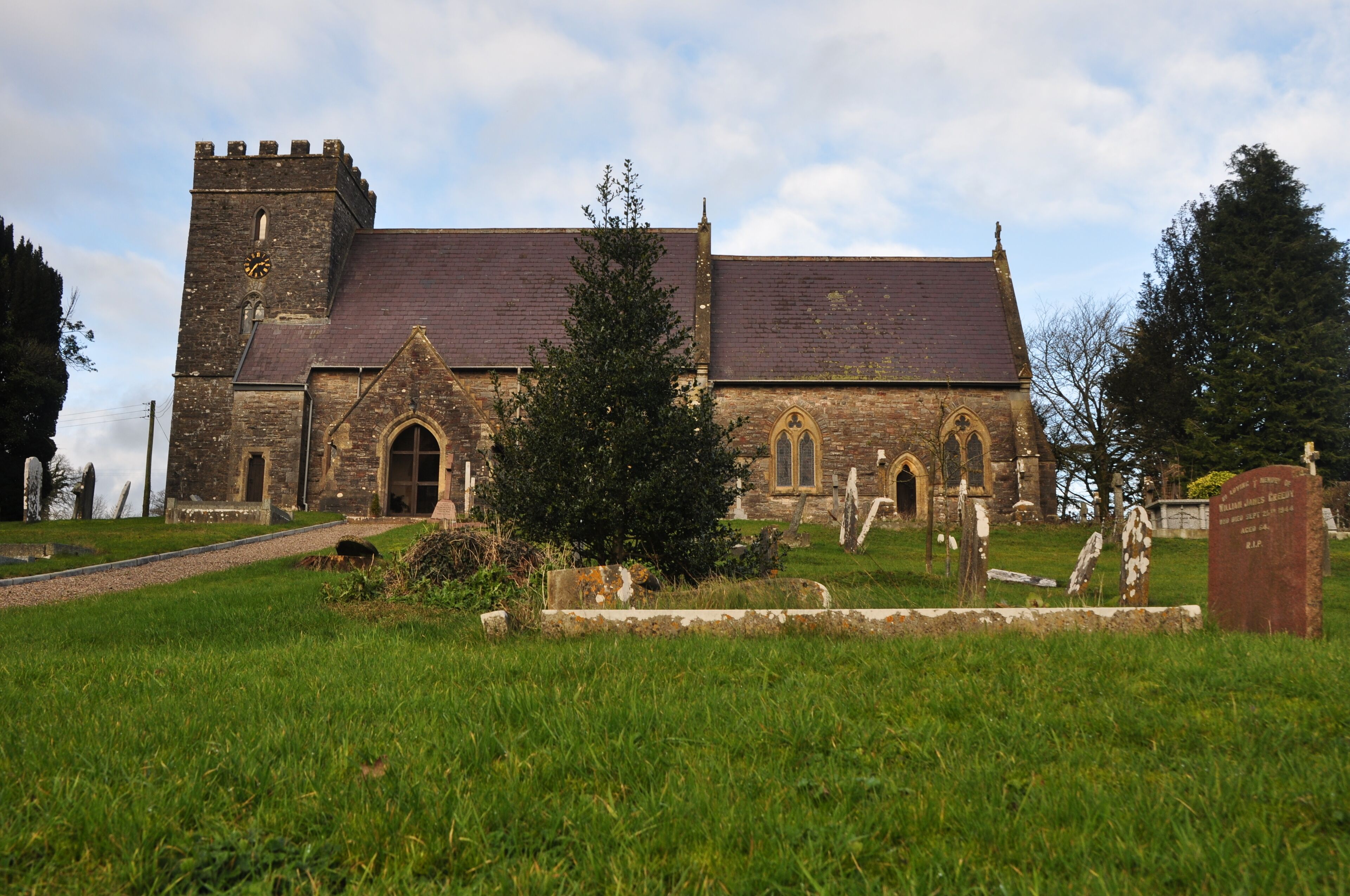 A historic church with a tower and arched windows, surrounded by a cemetery with headstones.