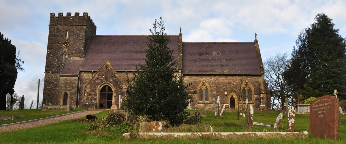 A historic church with a tower and arched windows, surrounded by a cemetery with headstones.