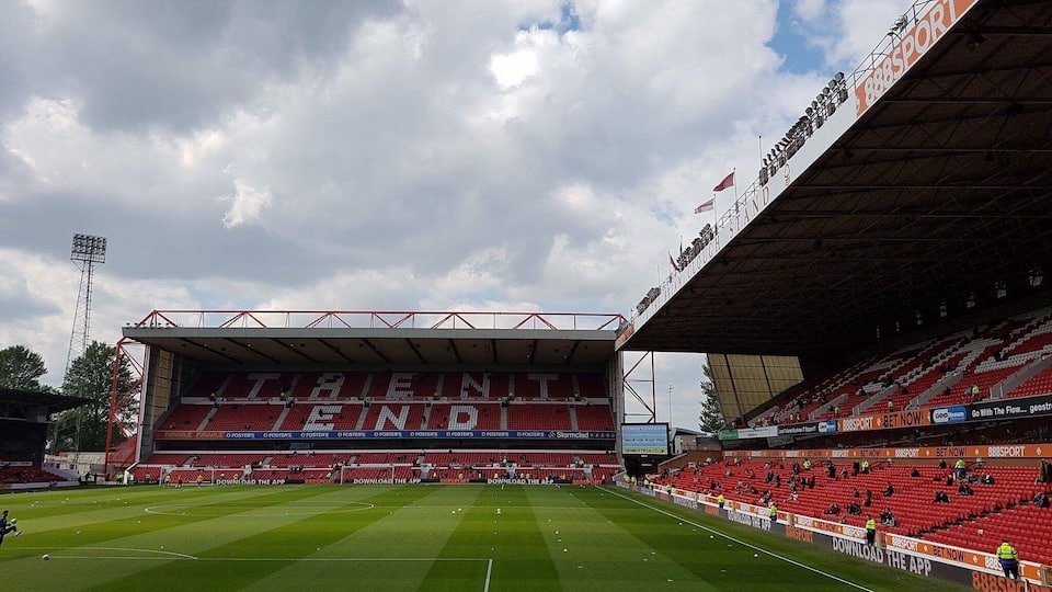 Un estadio de fútbol con asientos rojos y una gran pantalla digital.