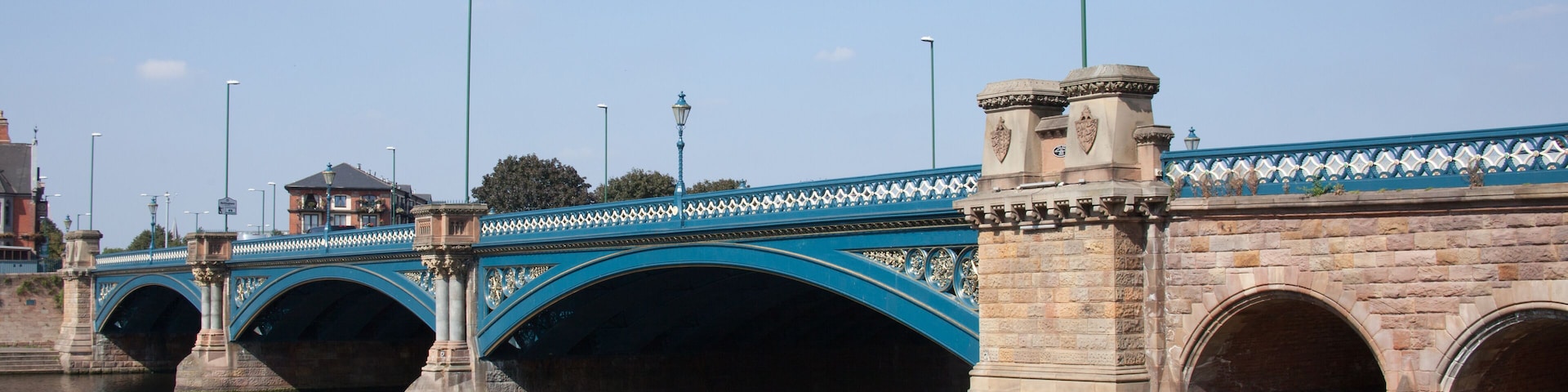 Uma ponte de pedra com arcos azuis sobre um rio.