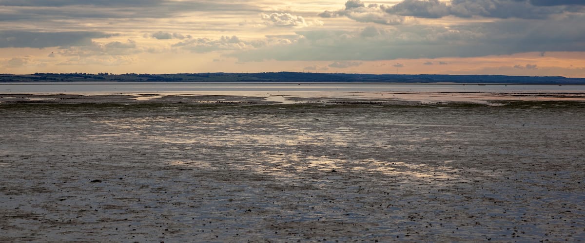 A beach with a cloudy sky and a distant shoreline.