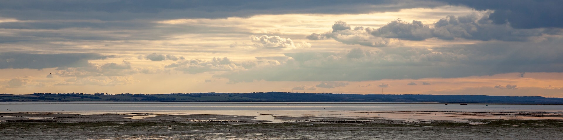 A beach with a cloudy sky and a distant shoreline.