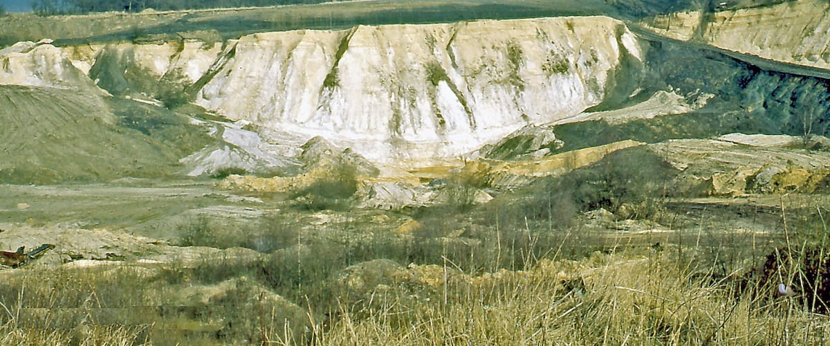 A barren landscape with a large, eroded hill and sparse vegetation.