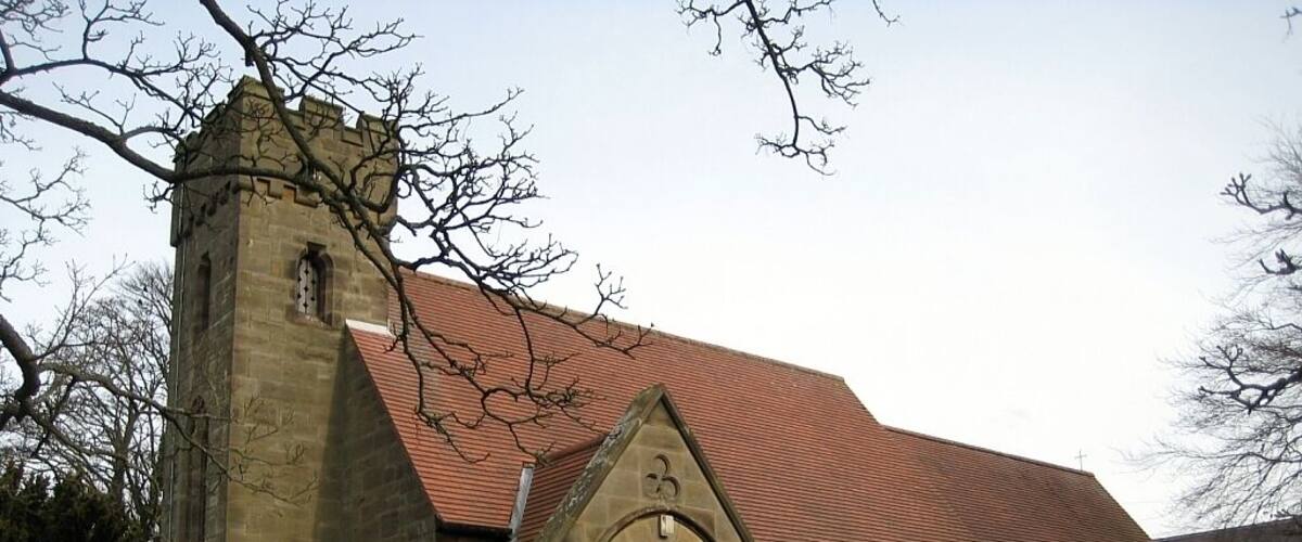 A stone church with a red-tiled roof and a bell tower.