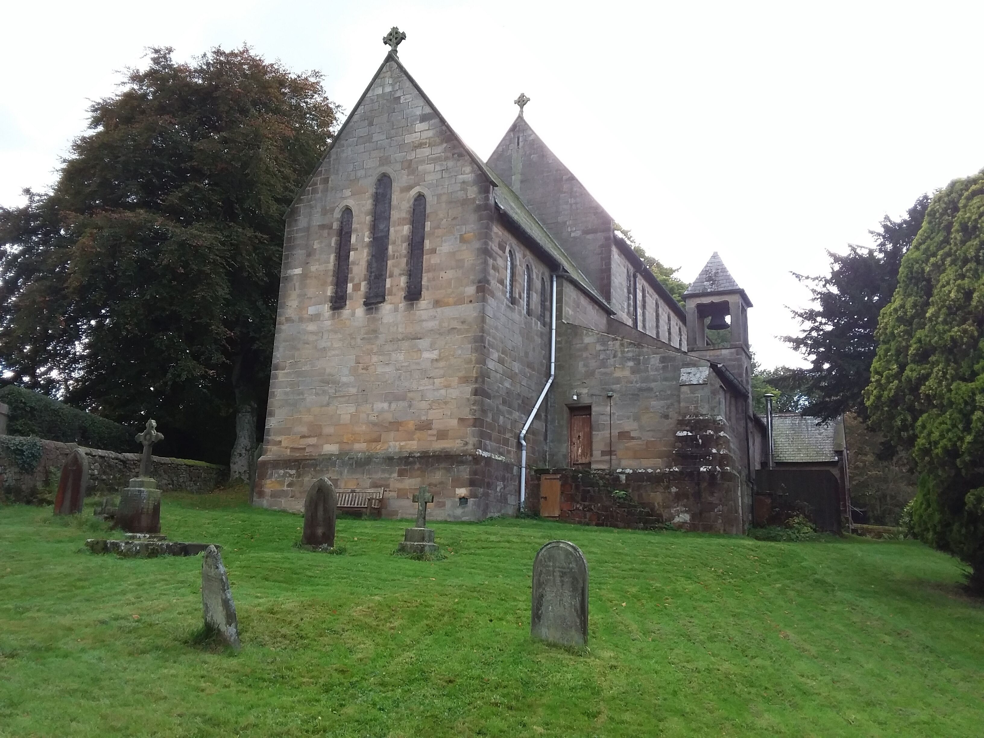 A stone church with a bell tower and a graveyard.
