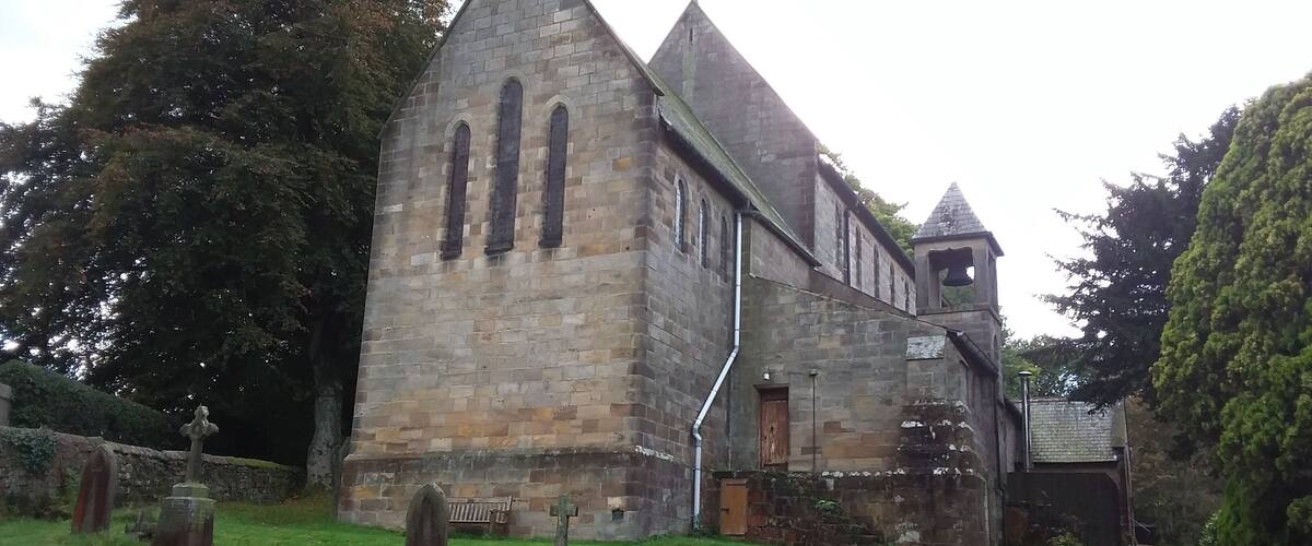 A stone church with a bell tower and a graveyard.