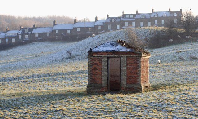 Ruin, Near Glaisdale This derelict building stands isolated in a field. It is square in plan but of quite an elaborate construction, slate roofed with distinctive brickwork used in the edging and corbelling. It was used as for the storage of blasting powder and is one of the few visible remains of the Glaisdale Ironstone Mine which operated from 1862 to 1874. The mine was a shaft mine, which has been capped and is located nearby, and ore was taken across a wooden bridge over the River Esk to the ironworks. In the distance is the houses of Carr End.