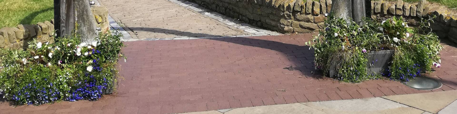 Un pueblo costero con un castillo histórico, un muro marítimo y un arco de metal.