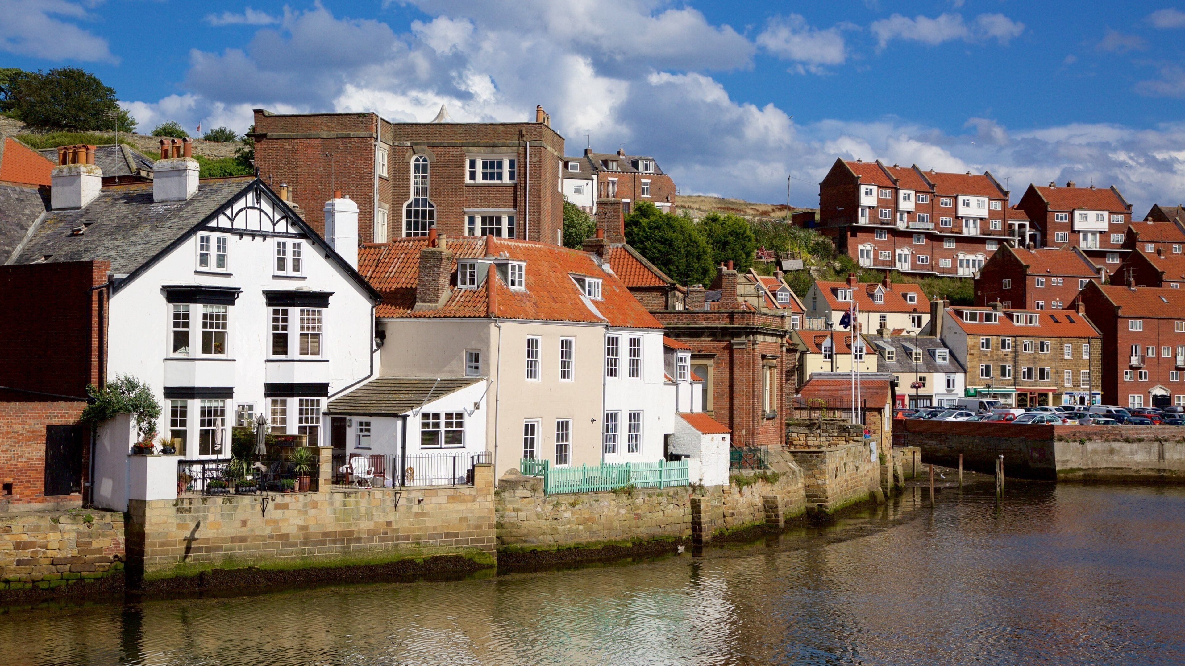 A riverside town with historic buildings, a stone wall, and a bridge.