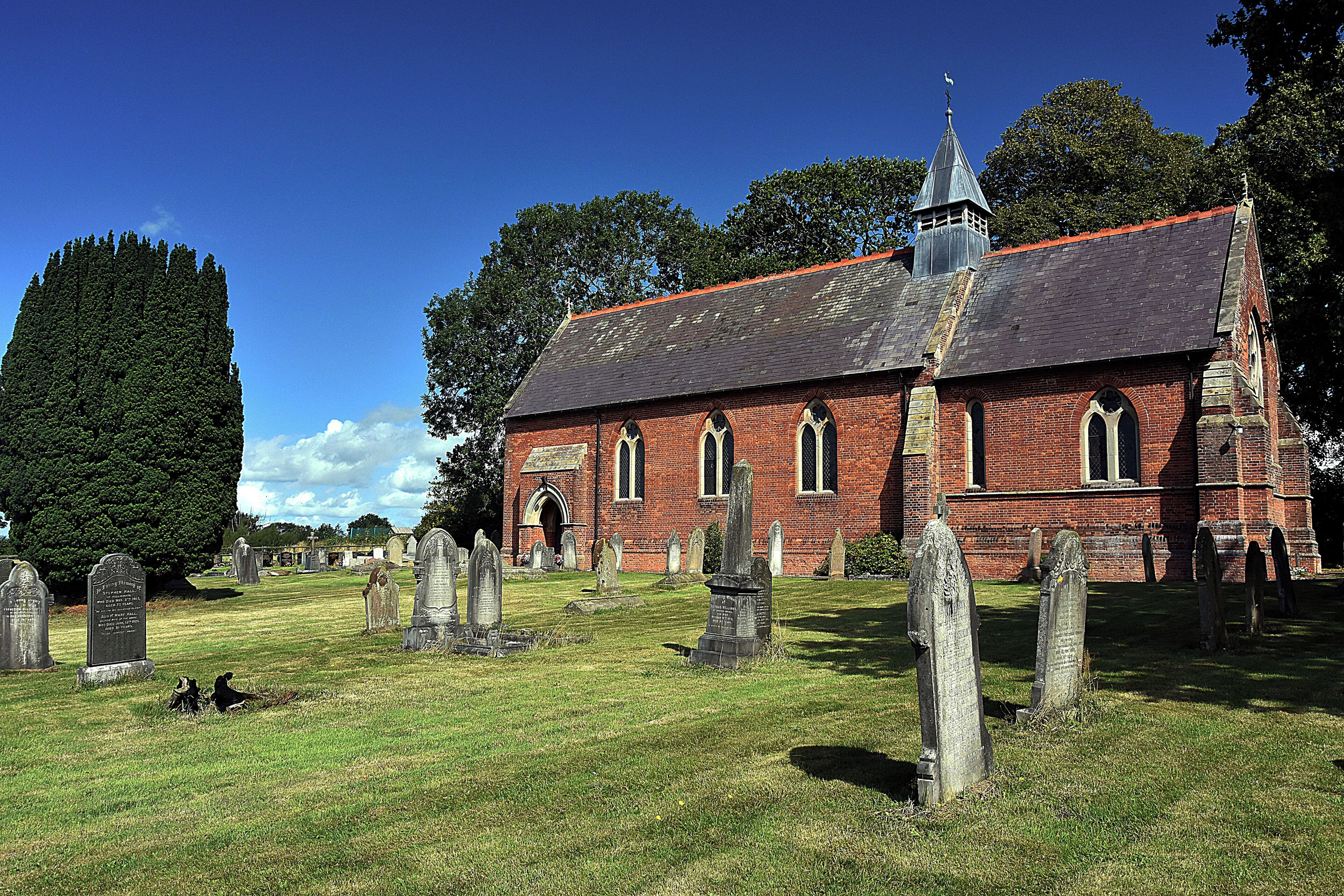 A church with a steeple and a graveyard with headstones.