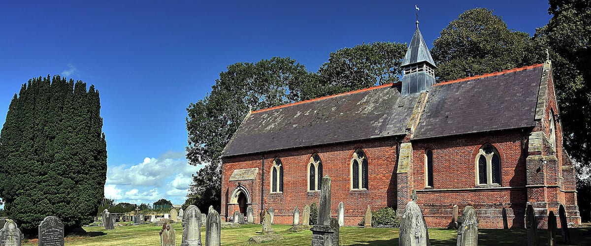 A church with a steeple and a graveyard with headstones.