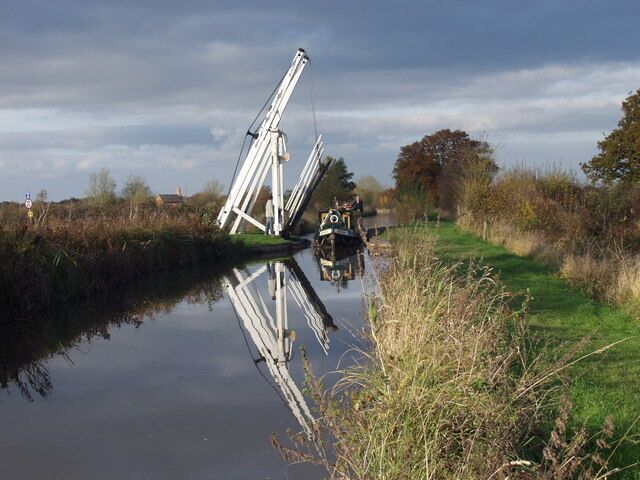 A calm river with a white crane and a small boat.