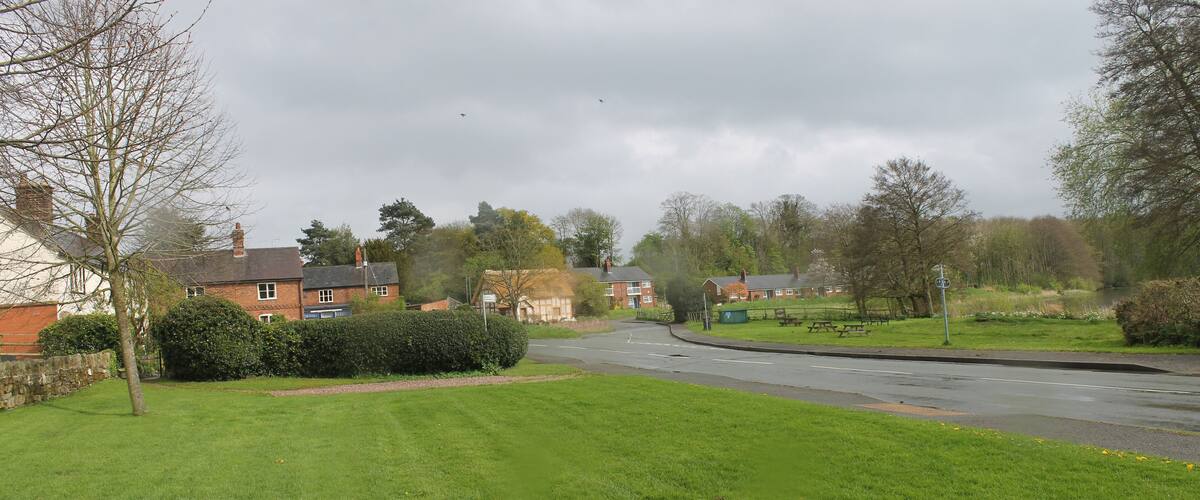 A suburban street with houses, a grassy area, and a river.