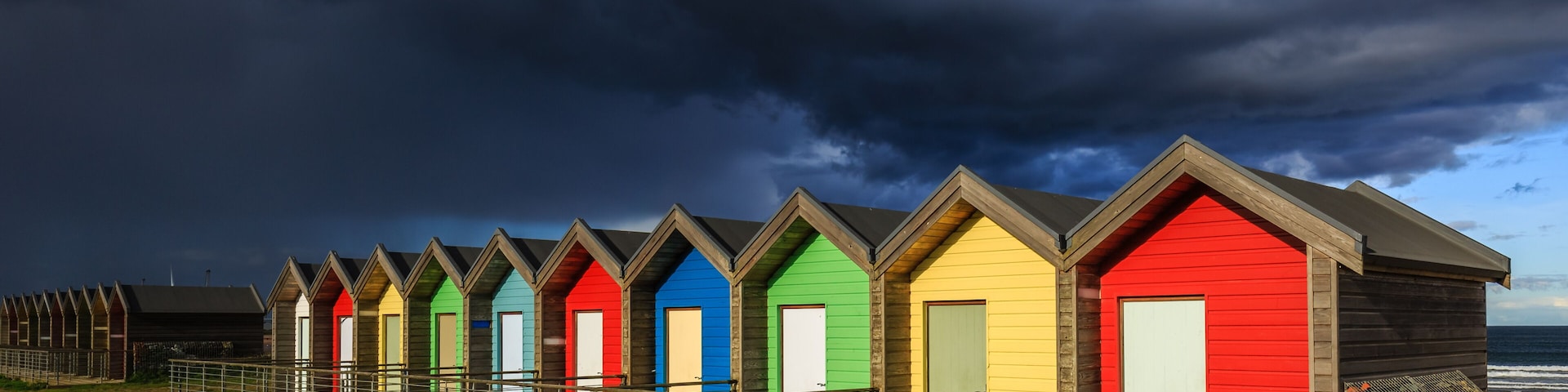 Threatening sky above Blyth beach huts, Northumberland, England