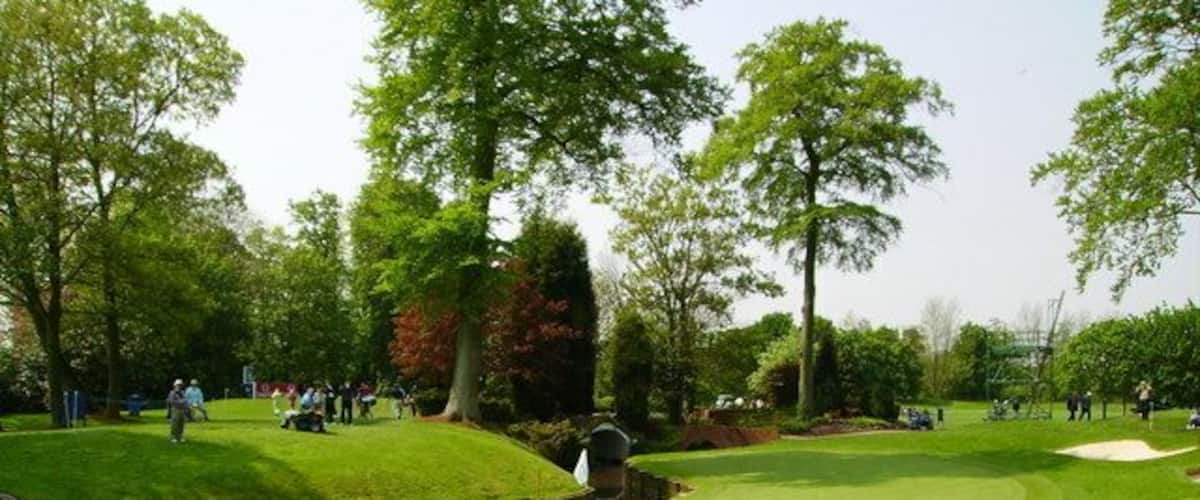 A golf course with a putting green, sand bunkers, and trees.