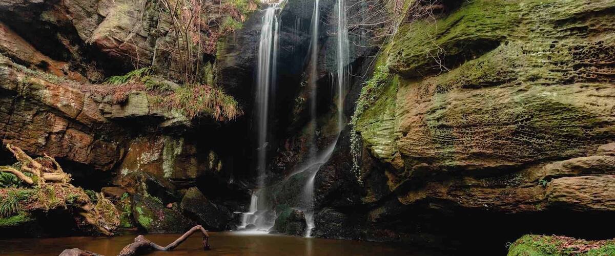 A waterfall cascading into a pool surrounded by moss-covered rocks.