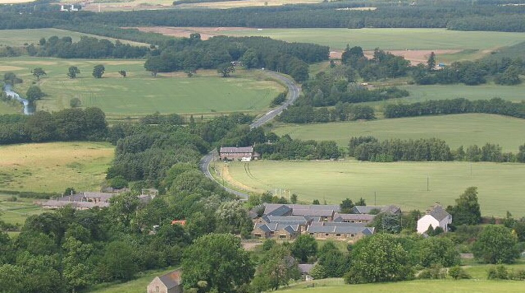 View over Akeld from the south. The large complex of buildings in the foreground of the photo is the country club 1248370, which dominatees the settlement. A little further along the main road is the old station 309714.